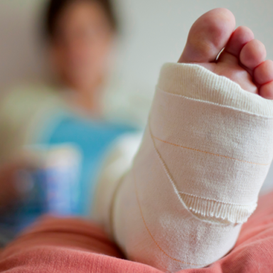 Woman with her plastered leg resting up on a cushion shot with a shallow depth of field focusing on the foot and toes.