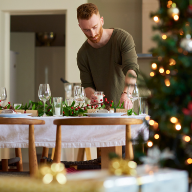 A man setting the table for a holiday dinner.