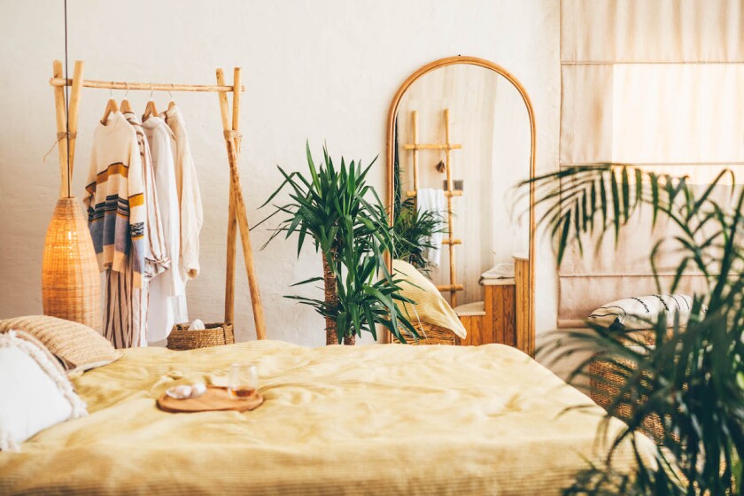 Clothes hanging on a hangers near a mirror at home.