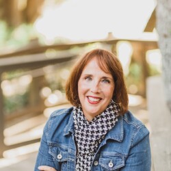 Donna Christiano Campisano sitting down with her arms crossed smiling at the camera